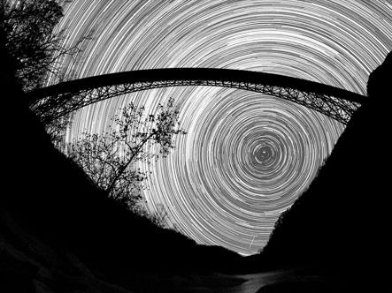 timelapse shot of the sky with a bridge in the foreground