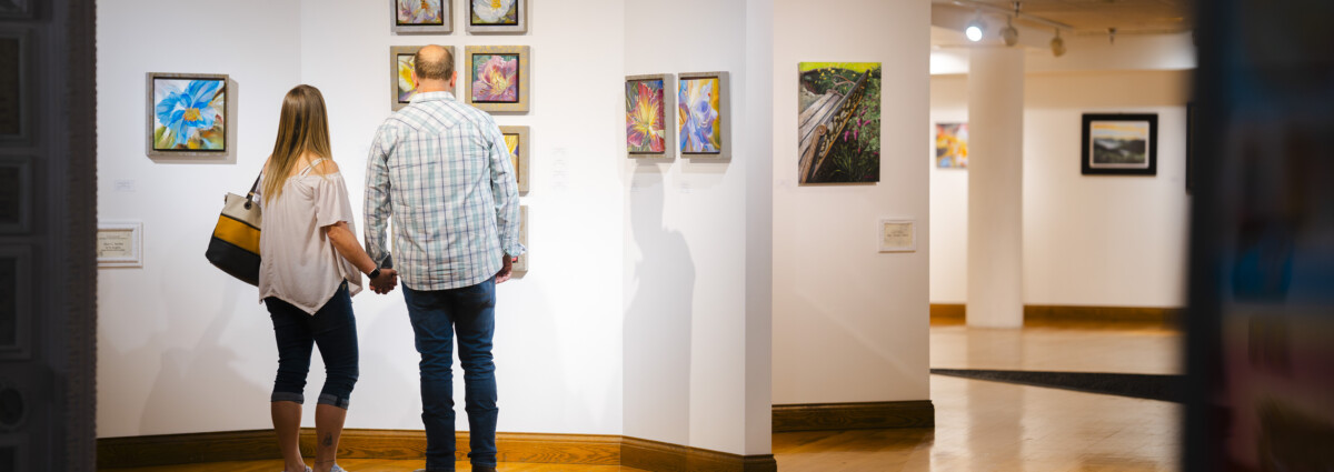 A golden age couple at the Parkersburg Art Center admiring a gallery.