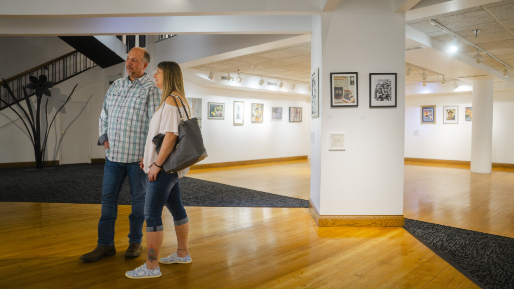 A man and a woman hold hands and admire artwork at the Parkersburg Art Center.
